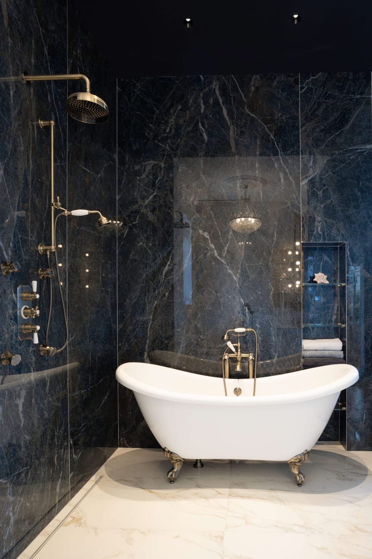 Dramatic black marble bath with white clawfoot slipper tub and brass fixtures