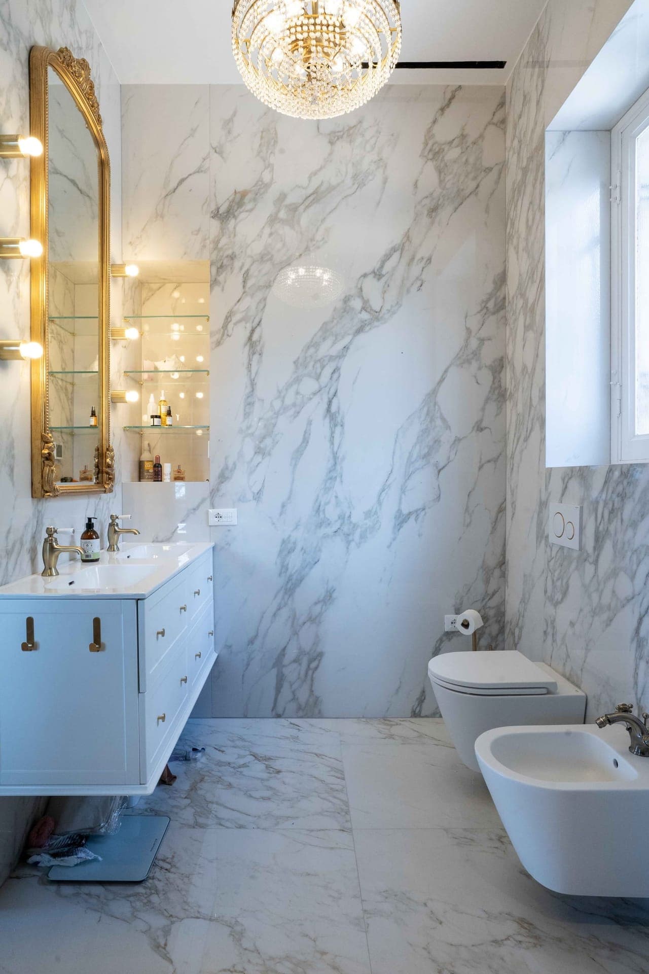 Calacatta marble bathroom with gilt mirror and crystal chandelier