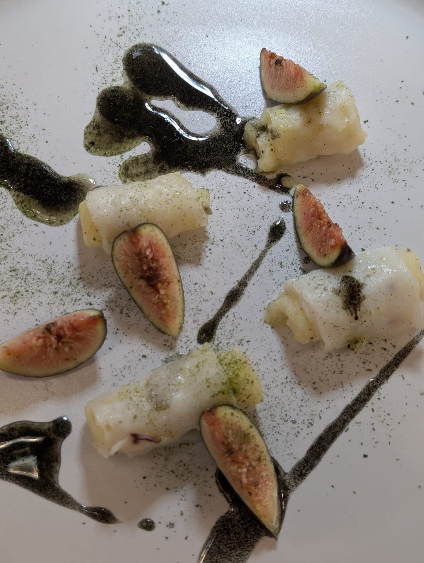 Fish and fig rolls with herb powder and dark sauce
