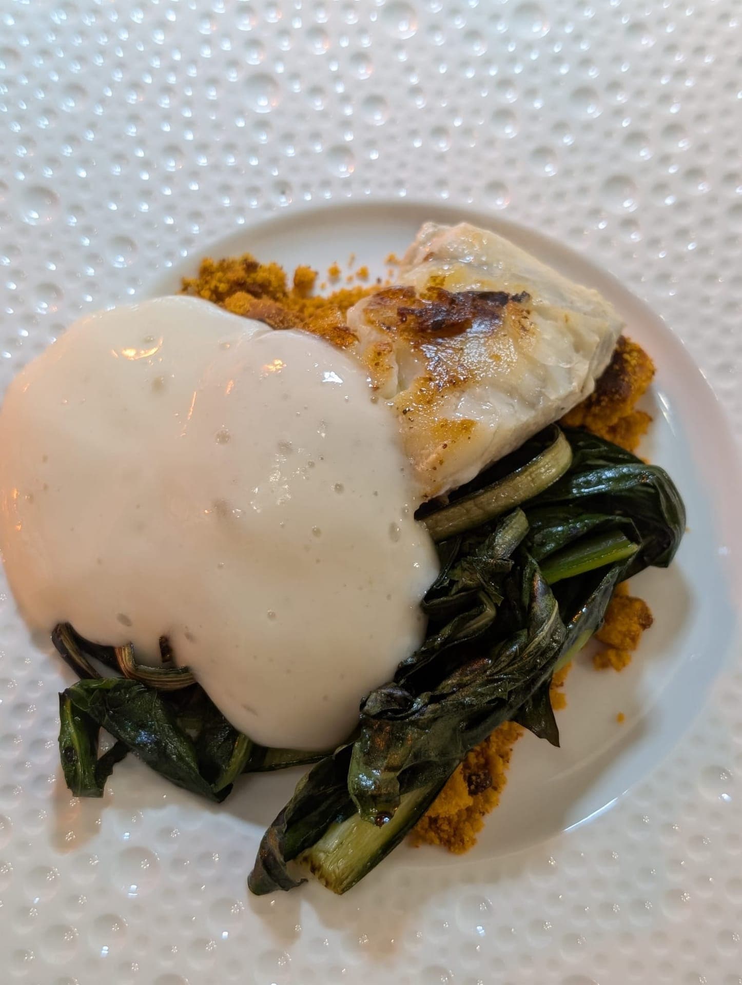 Seared fish over sautéed greens with cream sauce