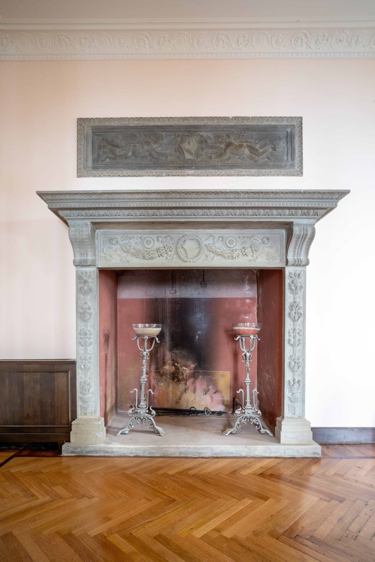 Carved stone Renaissance fireplace with cherub relief and herringbone parquet