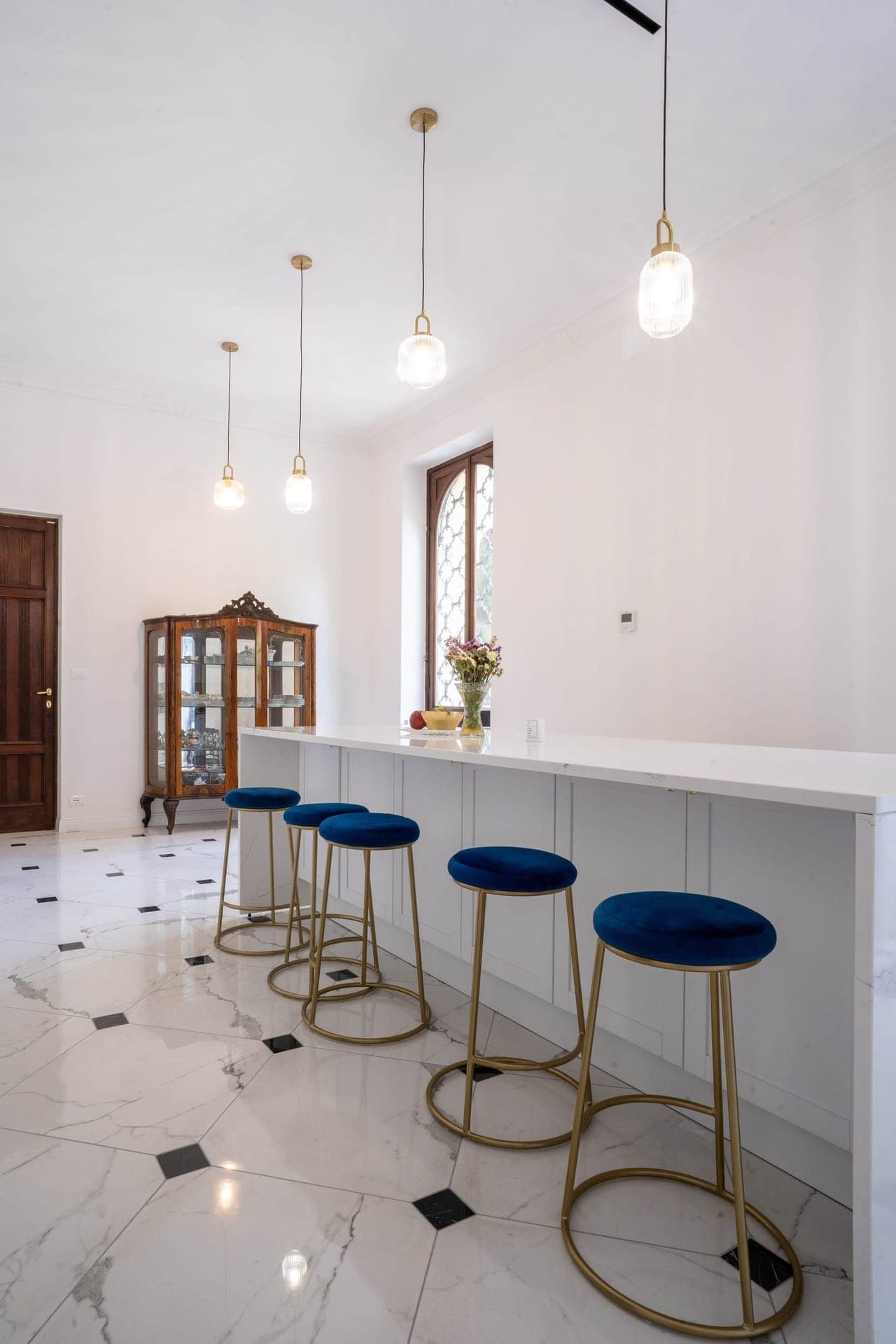Bright breakfast bar with marble counter and gold-legged blue stools