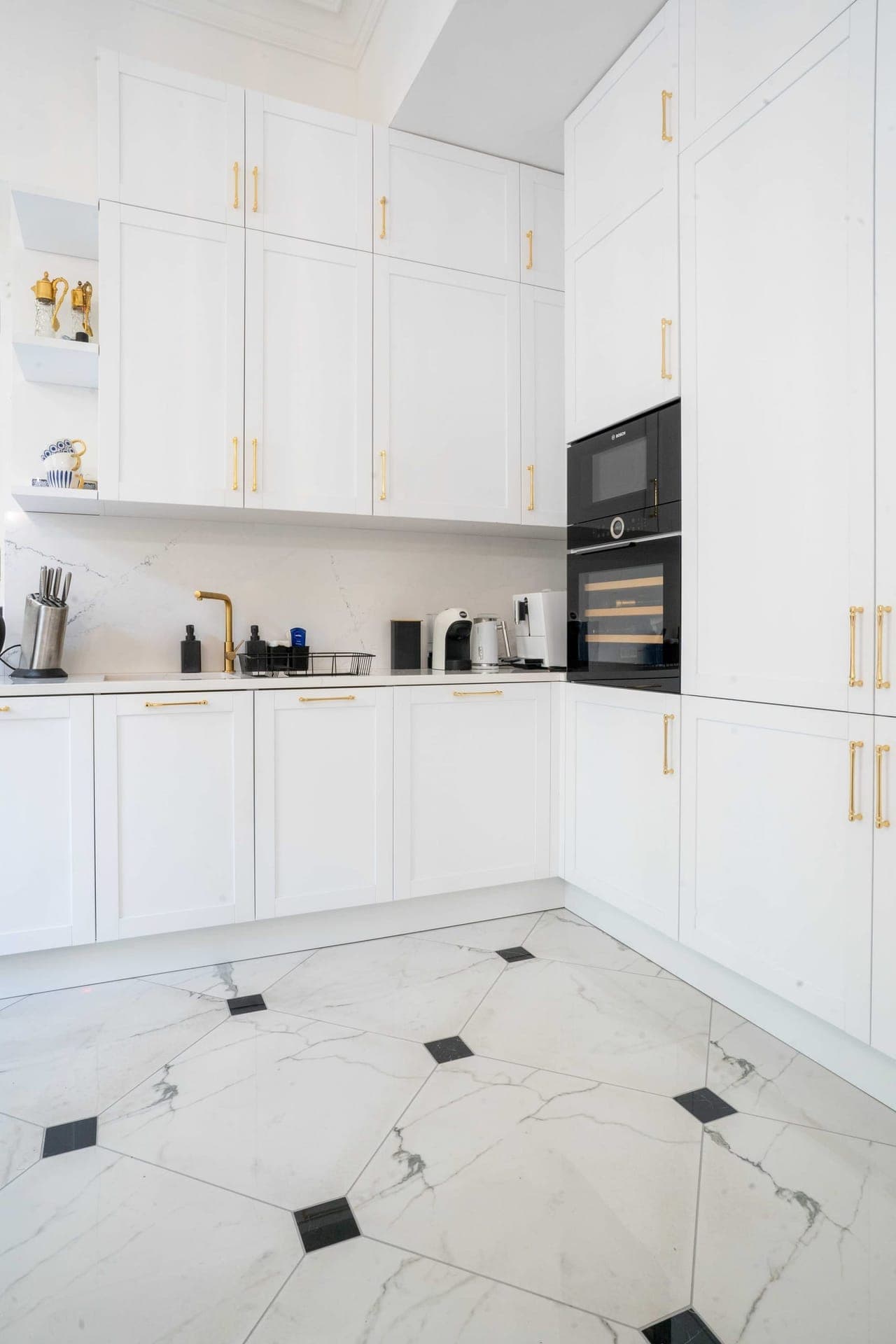 White shaker kitchen with brass handles and marble mosaic floor