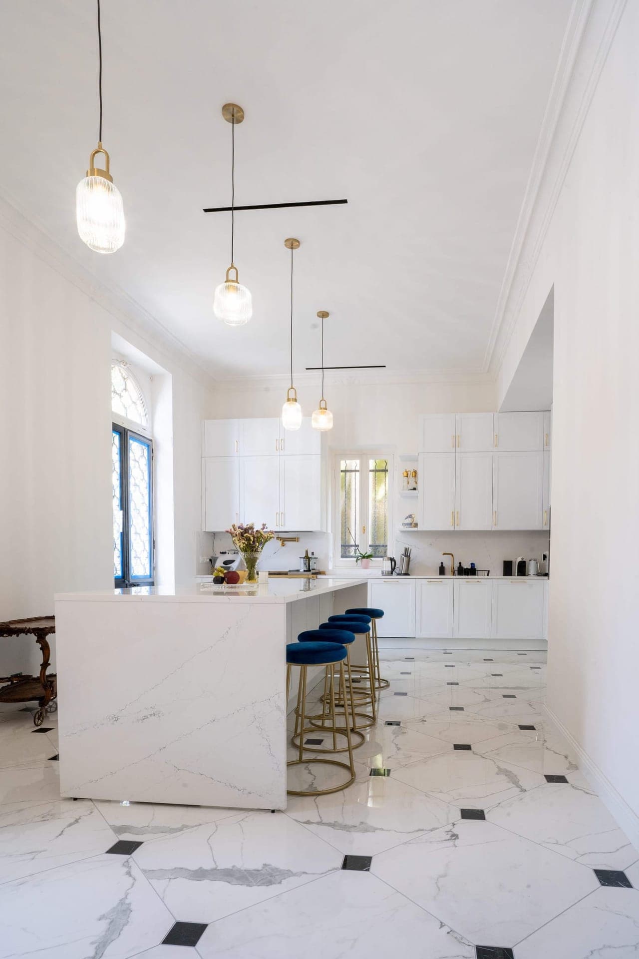 Open kitchen with white marble island and blue velvet bar stools