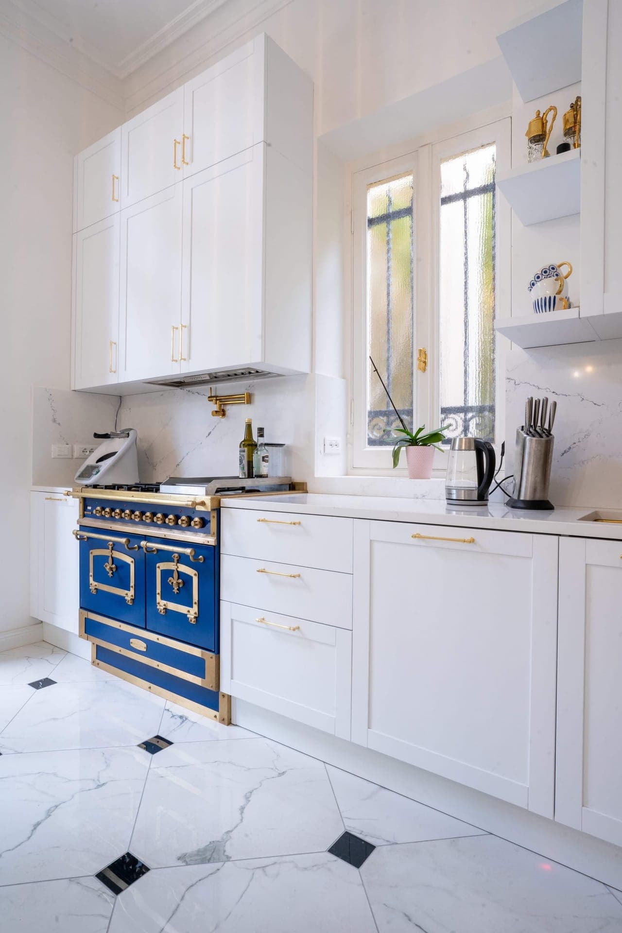 Kitchen with blue and brass range cooker against marble