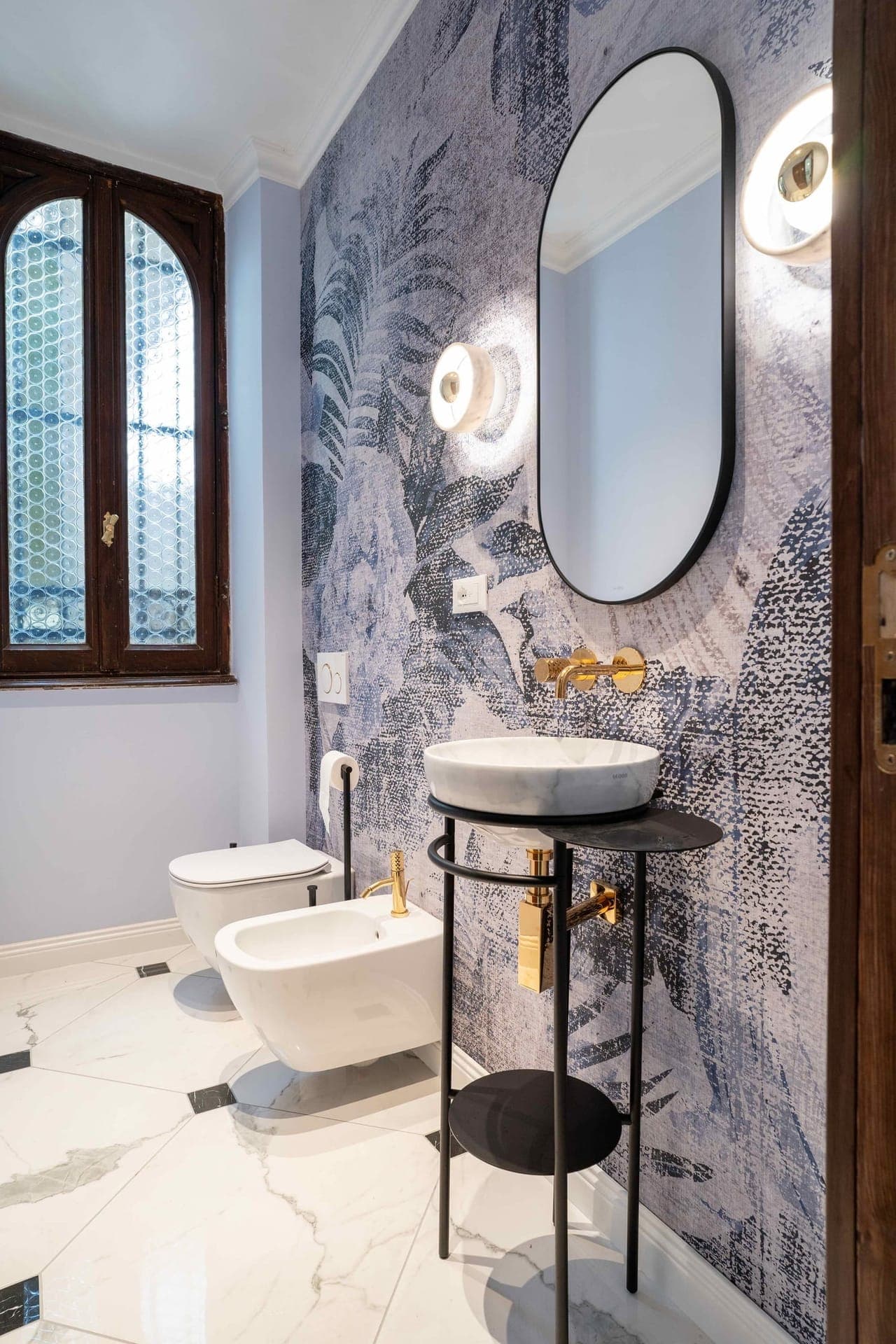 Powder room with tropical leaf wallpaper, marble vessel sink and stained-glass window